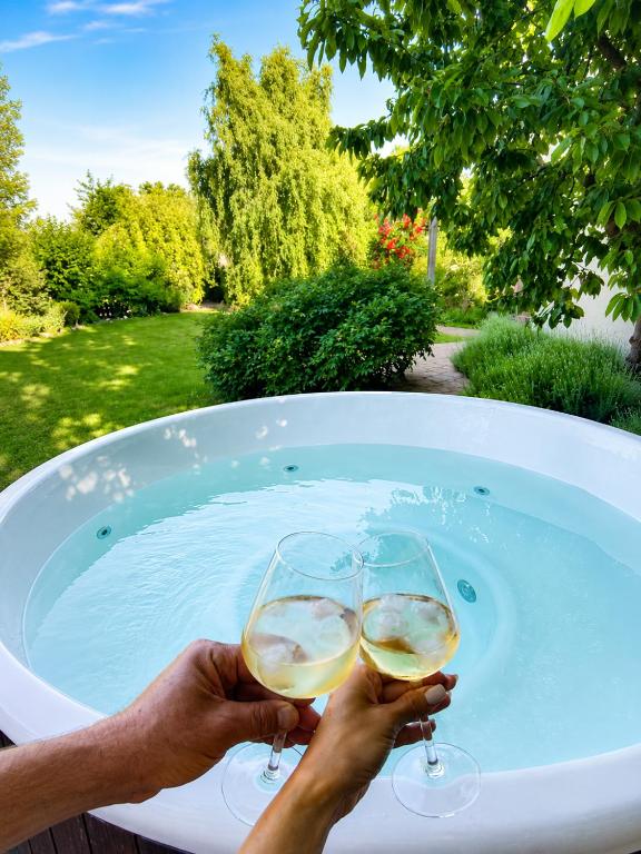 two people holding wine glasses in a bath tub at Villa del Grossa Будинок з каміном та чаном на дровах in Kuchakiv