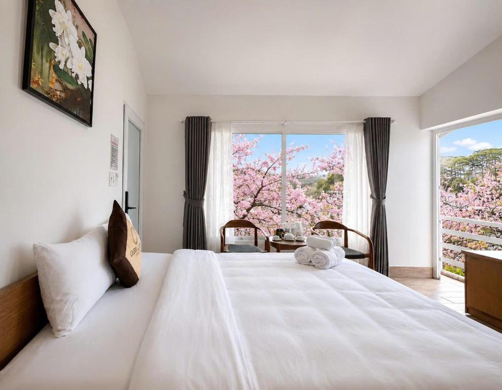 a bedroom with a large white bed with a window at Cherry Luxury Hotel in Da Lat