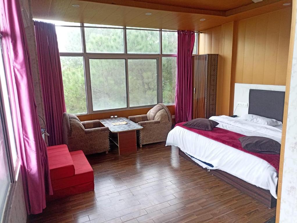 a bedroom with a bed and a large window at Hotel Pine View Villa in Dagshai