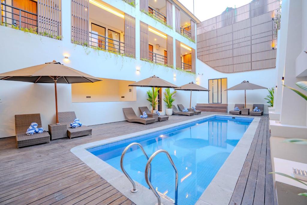 a pool in a hotel with chairs and umbrellas at Anandani Suites in Canggu
