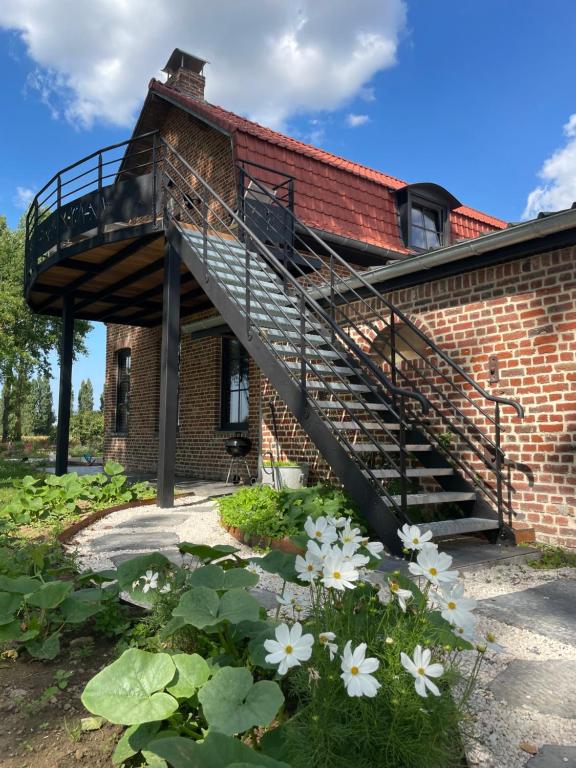 a brick building with a staircase and white flowers at La ferme des peupliers in Estaires
