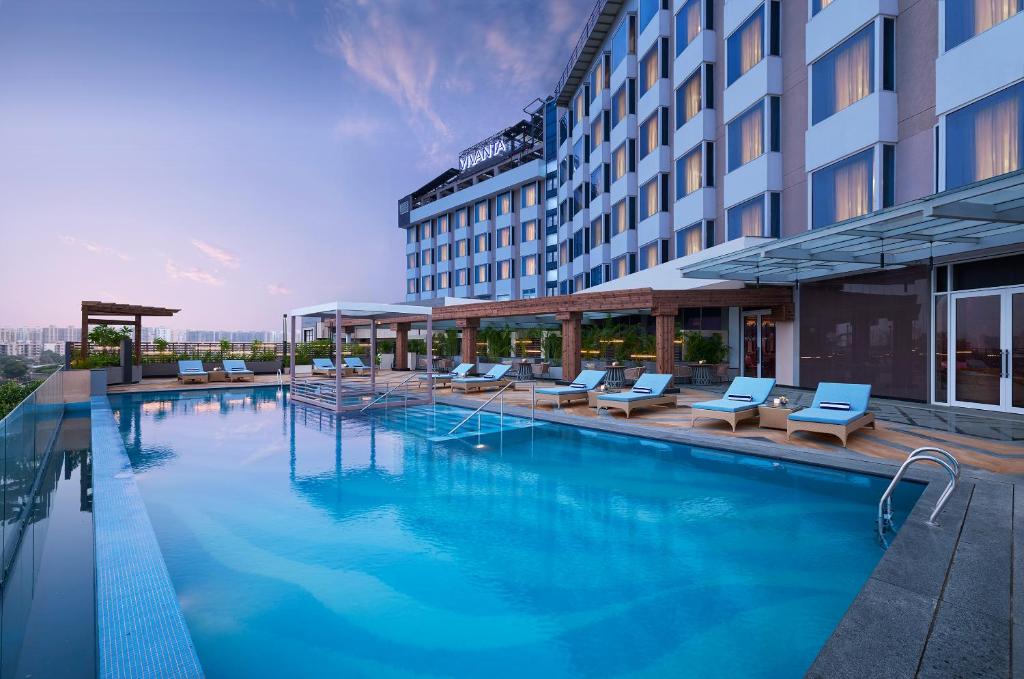a large swimming pool with lounge chairs and a hotel at Vivanta Gurugram Sector 95A in Gurgaon