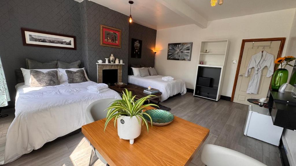 a bedroom with two beds and a table and a tv at The Cloud in Alderley Edge