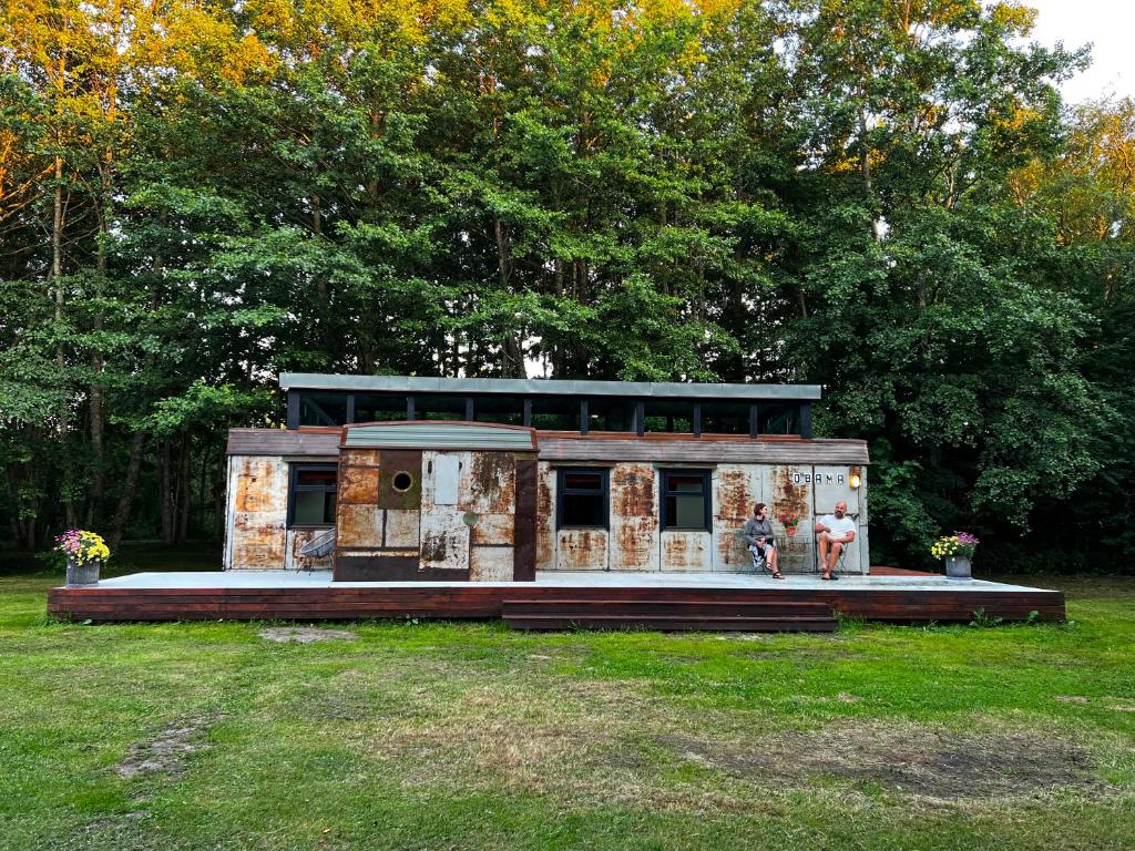 ein Spielzeughaus mit zwei Personen, die im Gras stehen in der Unterkunft 0'Bama - Unique Upcycled Tiny House in Selgas