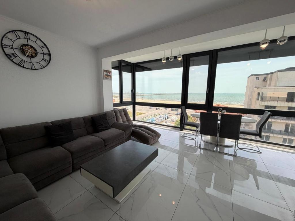 a living room with a couch and a clock on the wall at Luxury apartment with sea view in Mamaia Sat/Năvodari