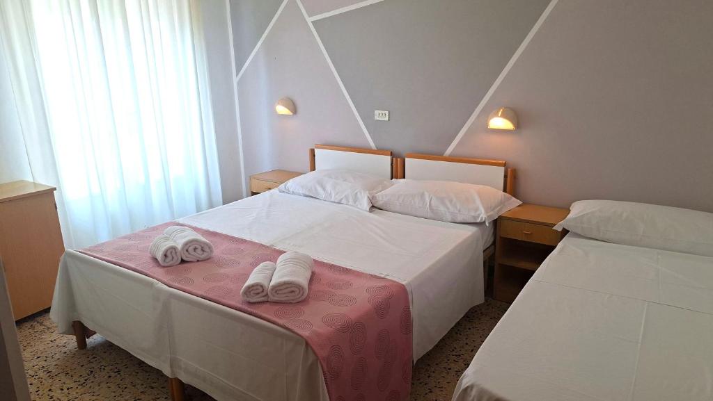 a hotel room with two beds with towels on a table at Hotel Astoria in Riccione