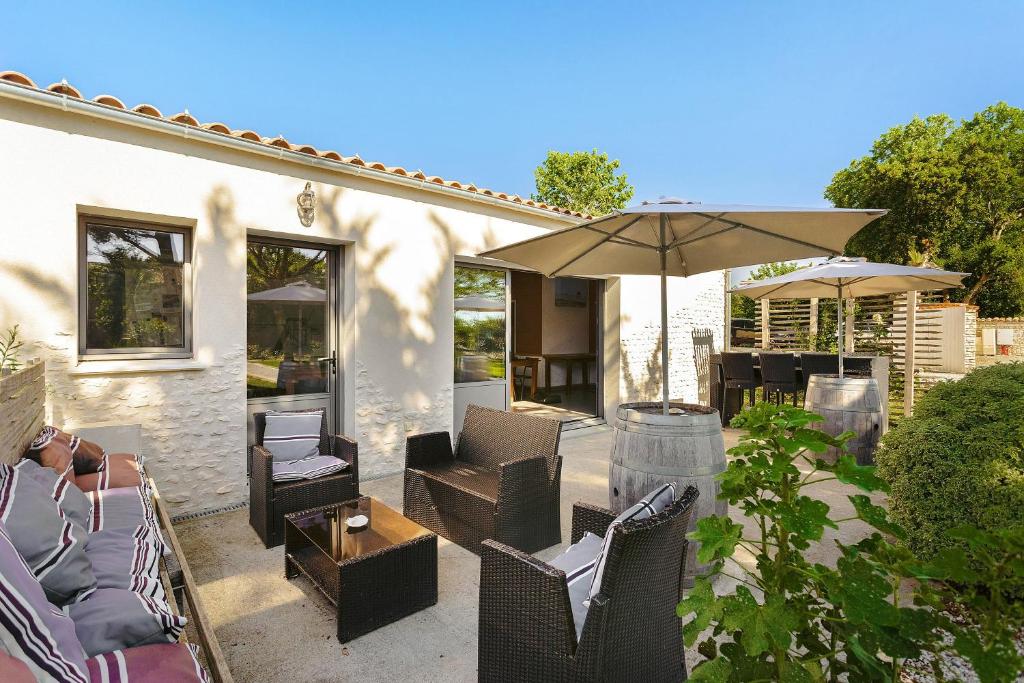 an outdoor patio with chairs and an umbrella at Domaine Roses Des Sables in La Jarrie