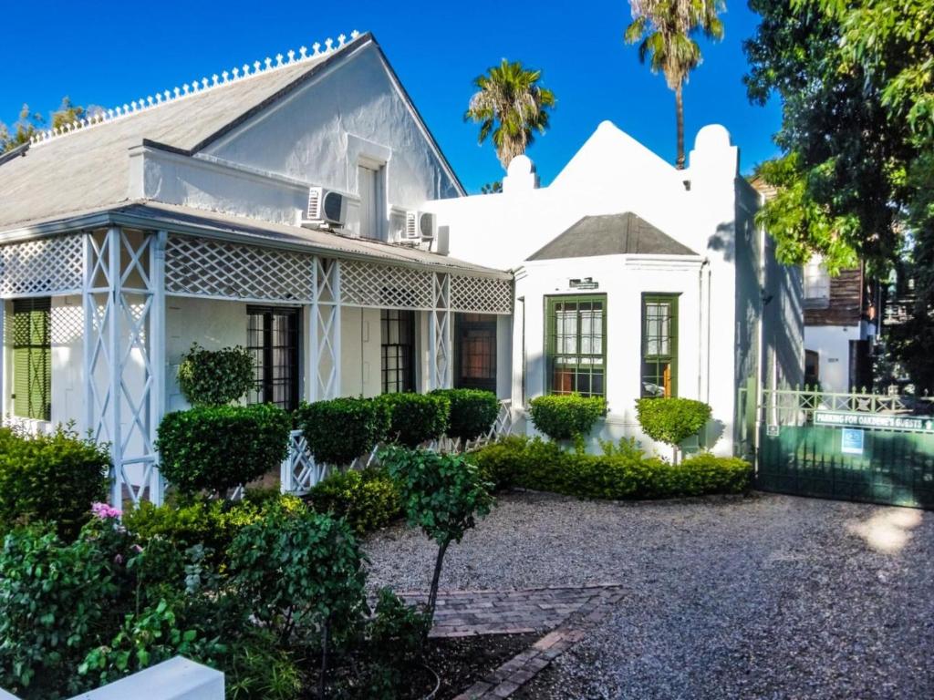 an old white house with trees and bushes at Oakdene Guest House in Oudtshoorn