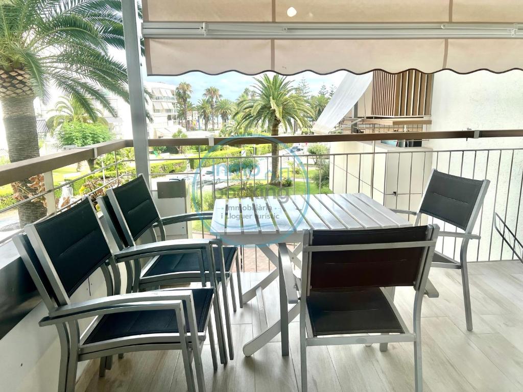 a table and chairs on a balcony with palm trees at Beach Formentor salou in Salou