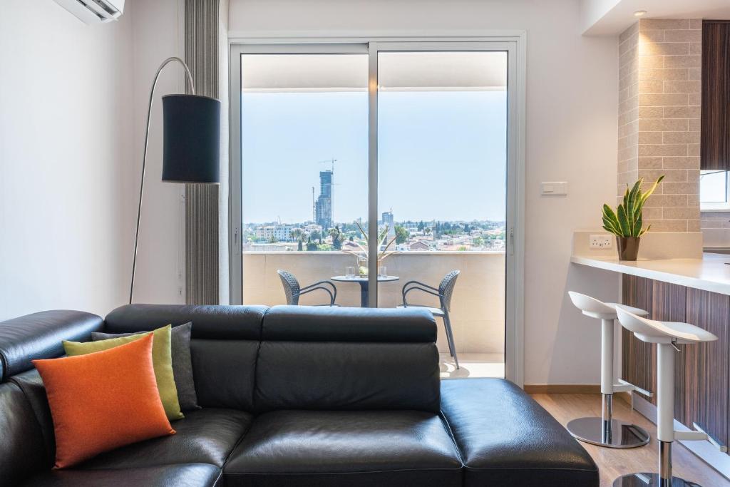 a living room with a black leather couch and a table at Limassol Marina Seaview Suite in Limassol