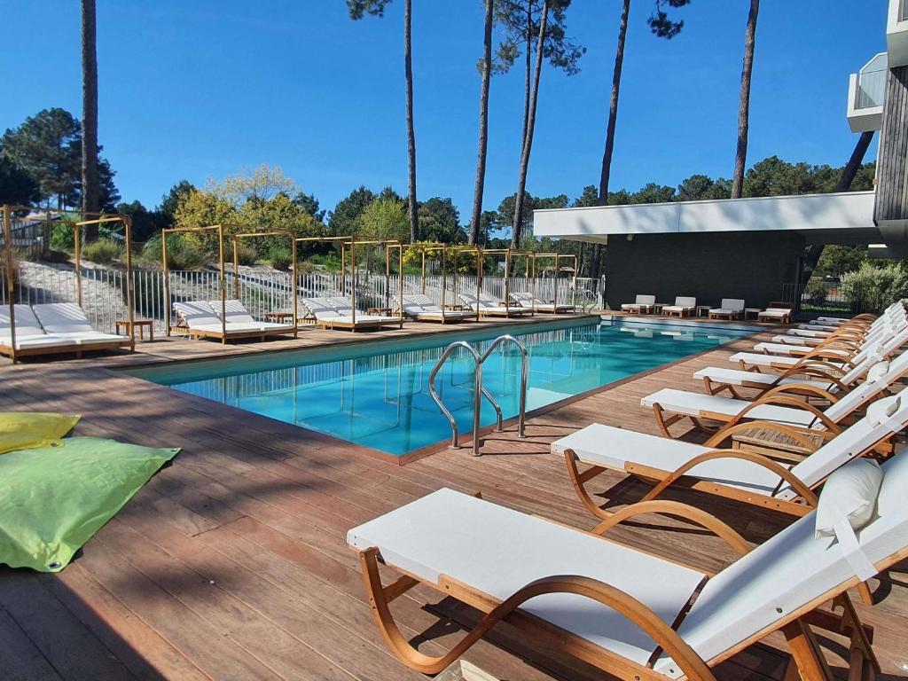a row of lounge chairs next to a swimming pool at ibis Styles Arcachon Gujan Mestras in Gujan-Mestras