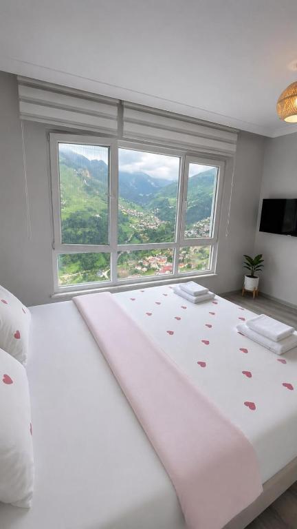 a bedroom with a large white bed with a large window at Hamsiköy Doruk Apart in Macka