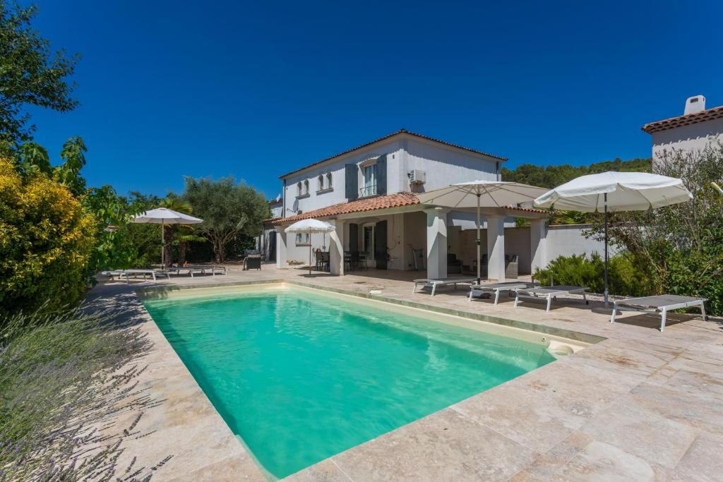 a pool in front of a house with umbrellas at Villa Etoile in Cabasse
