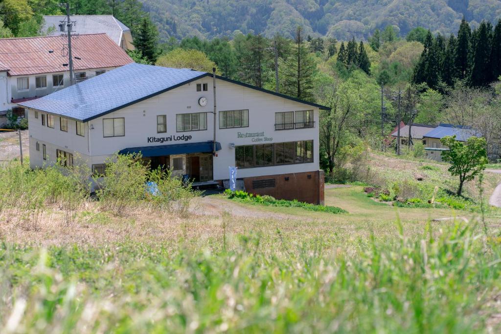 a large white house in the middle of a field at 北国ロッヂ in Otari