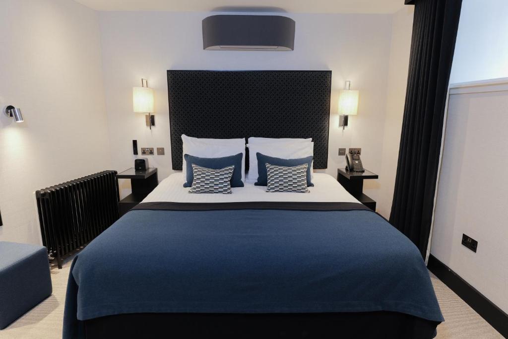 ein Schlafzimmer mit einem großen Bett, bezogen mit blauen Laken und Kissen. in der Unterkunft The Chester Hotel in Aberdeen