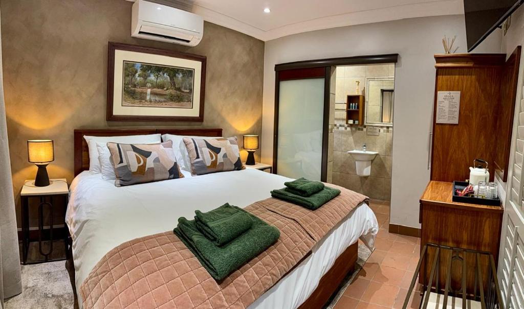 a bedroom with a large bed with green towels on it at Be Our Guest Accommodation in Klerksdorp