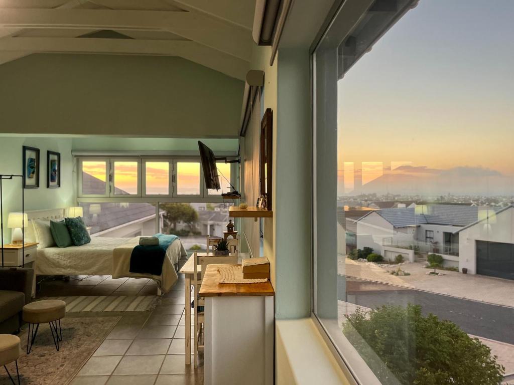 a living room with a bed and a large window at The Sundowner Room in Langebaan