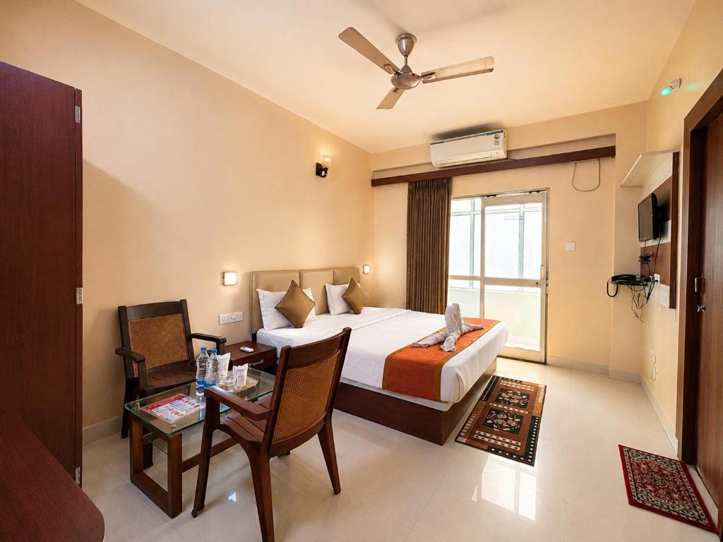 a hotel room with a bed and a table and a bed and a window at Hotel Golden Wave Puri - Baliapanda Housing Colony - Near Golden Beach- Parking - Restaurant in Puri