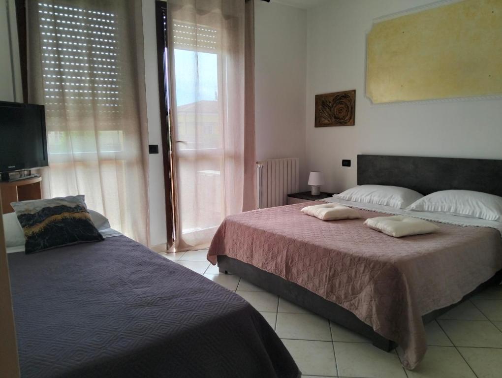 a bedroom with two beds and a tv and a window at Appartamento ai Noci in Padova