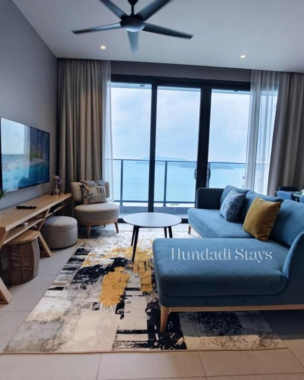 a living room with a blue couch and a tv at 4BR Beachfront Pantai Cenang Langkawi in Pantai Cenang