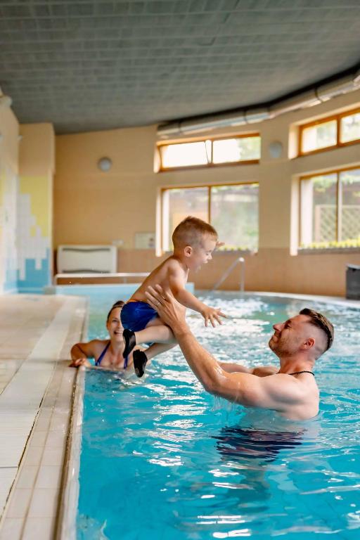a man and a woman and a child in a swimming pool at Sojka Resort in Bešeňová