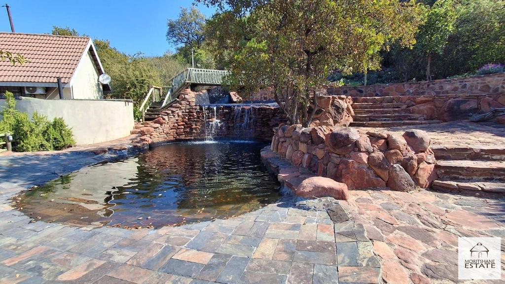 a small pond with a waterfall in a yard at Moritshane estate in Gaborone