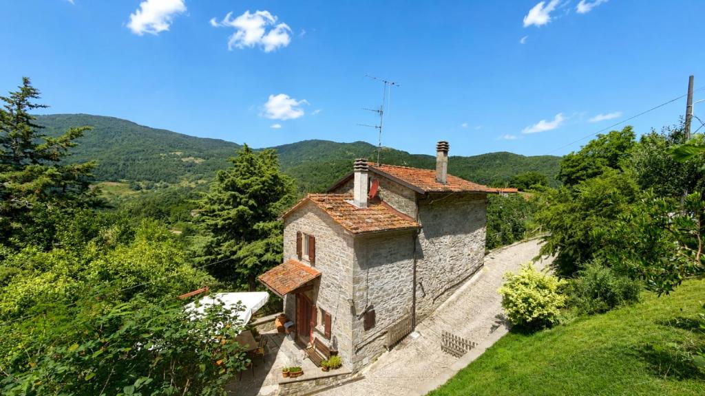 Ein altes Steinhaus auf einem Hügel mit Bergen im Hintergrund in der Unterkunft Poet's Rest in Pieve Santo Stefano