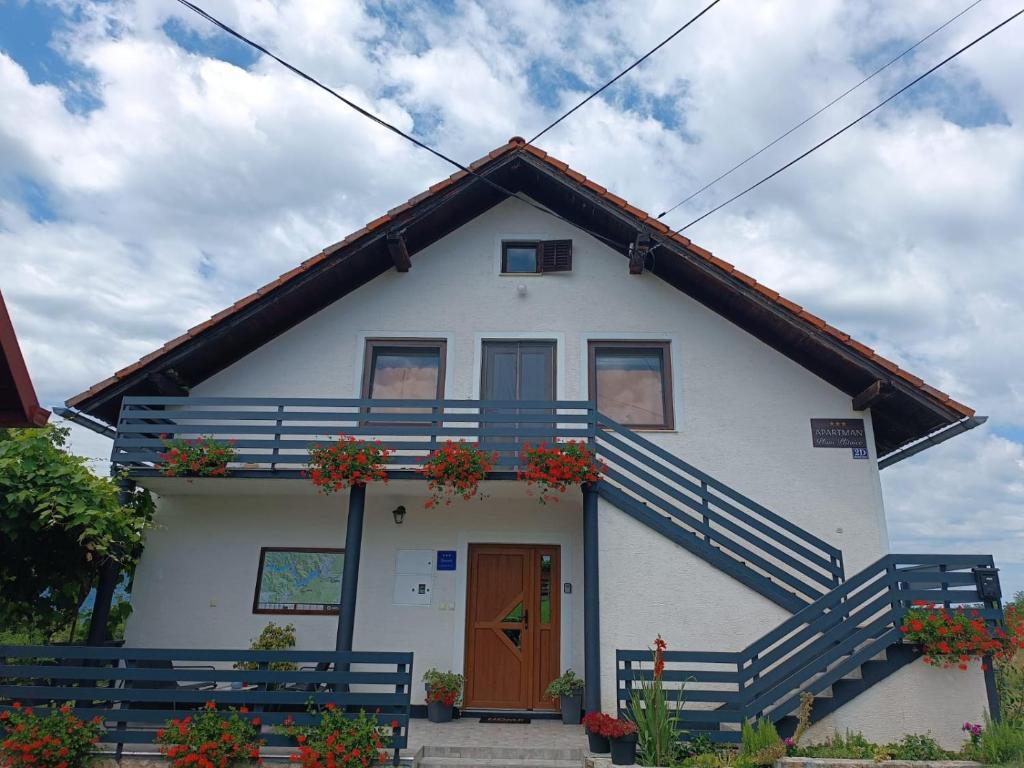 a white house with flower boxes on the front of it at Apartman PLUM PLITVICE in Drežnik Grad