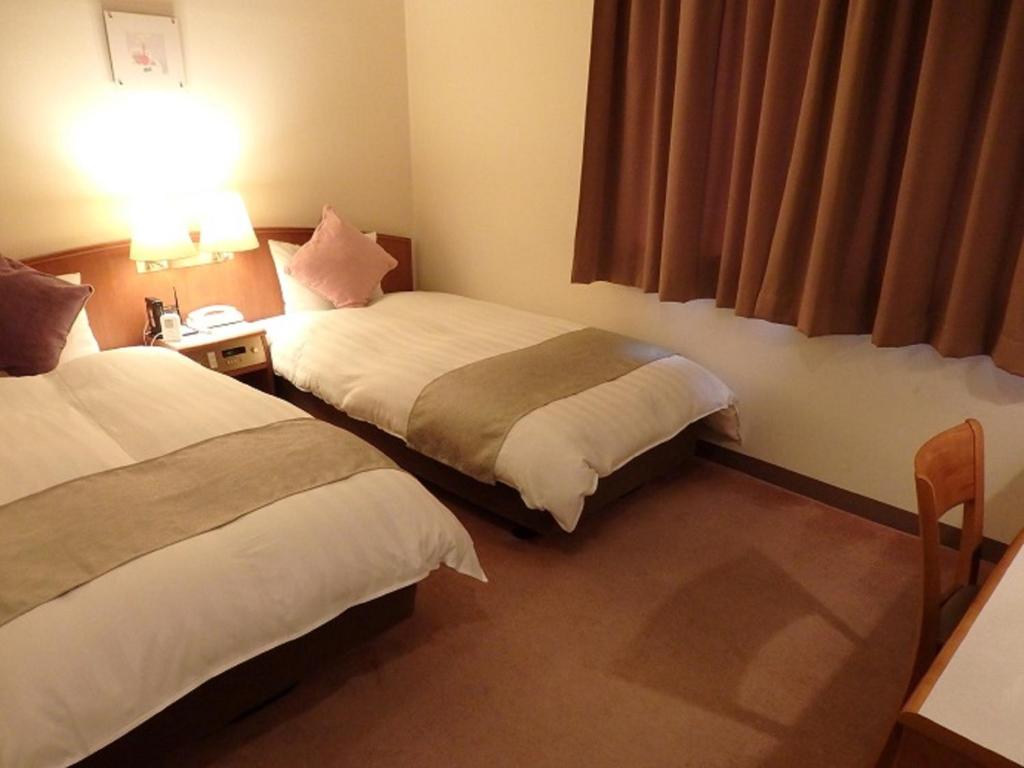 Ishiokaにあるホテル橋本楼のベッド2台と窓が備わるホテルルームです。