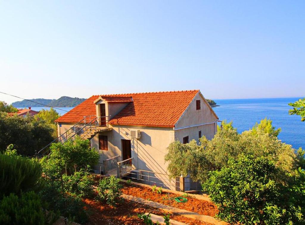 a house with an orange roof sitting on a hill at Apartments Bacic in Prizba