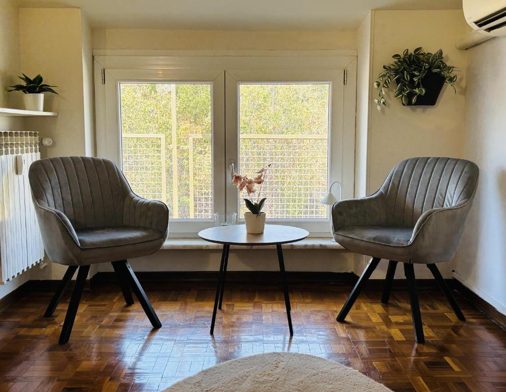 two chairs and a table in a room with a window at Station -Mansarda in posizione strategica, vista panoramica, letto king size e clima in Ivrea