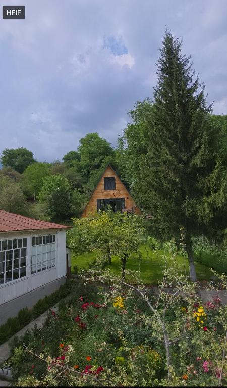 a wooden house with a yard with flowers at Riverside Guest house Mashkhur in Arslanbob