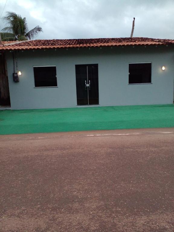 a white house with two doors and a green yard at Casa veraneio in Soure