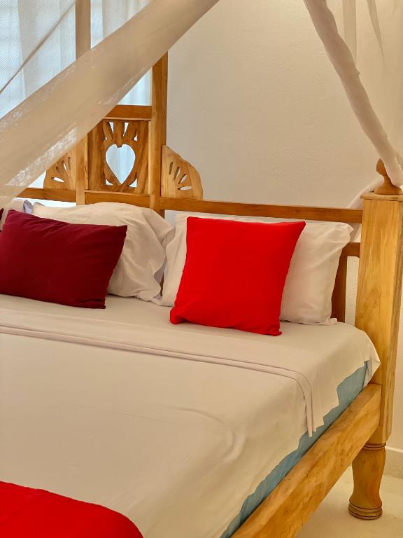 a bedroom with a bed with red pillows at Ocean view in Watamu