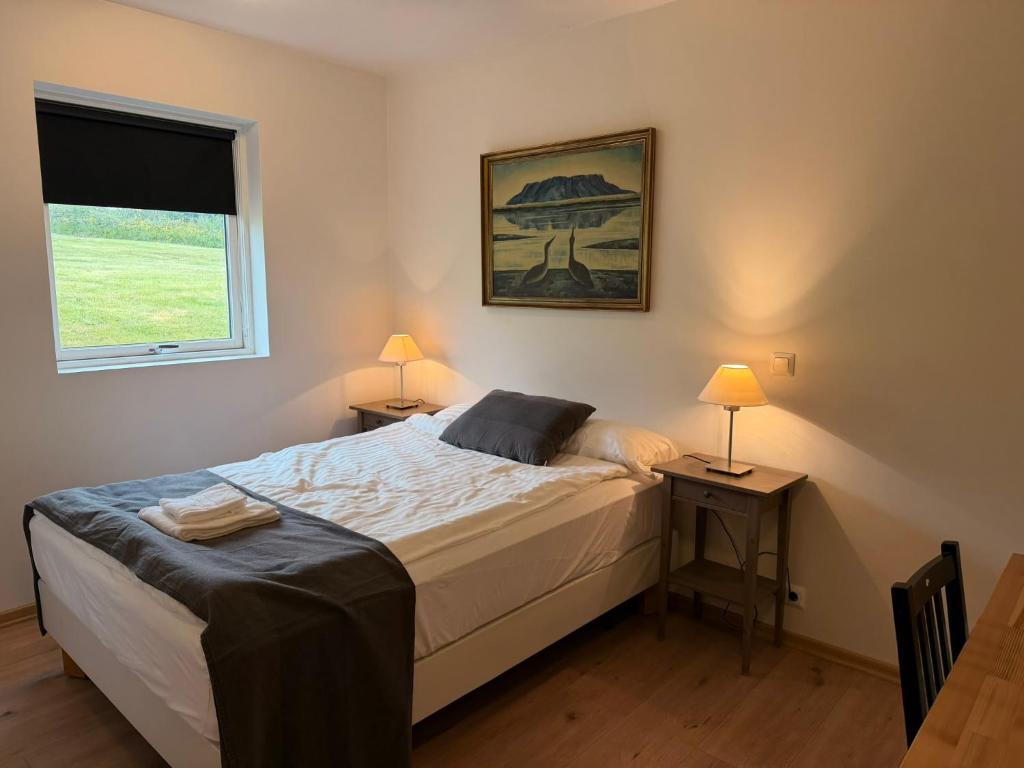 ein Schlafzimmer mit einem Bett und zwei Tischen mit Lampen in der Unterkunft Stöð-INN in Stöðvarfjörður