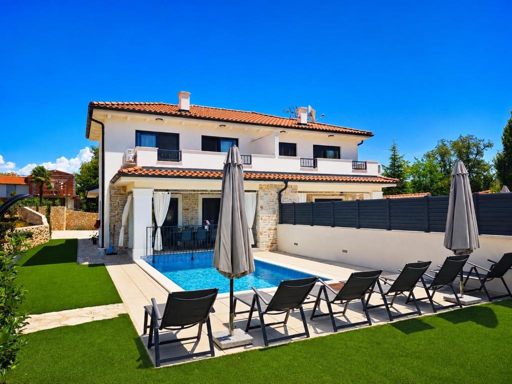 a pool with chairs and umbrellas in front of a house at Villa Dijana with Pool - Sol Tours in Kras