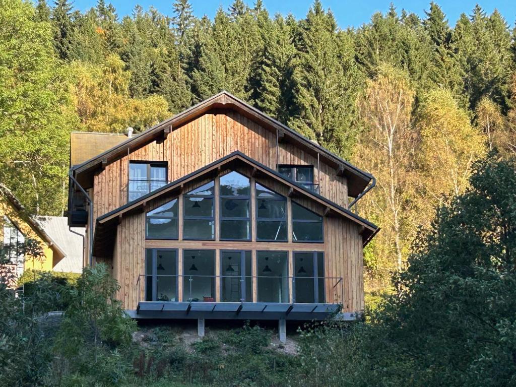 a house with a large window in the forest at Harrachovský Chalet Gryf u sjezdovky in Ryžoviště