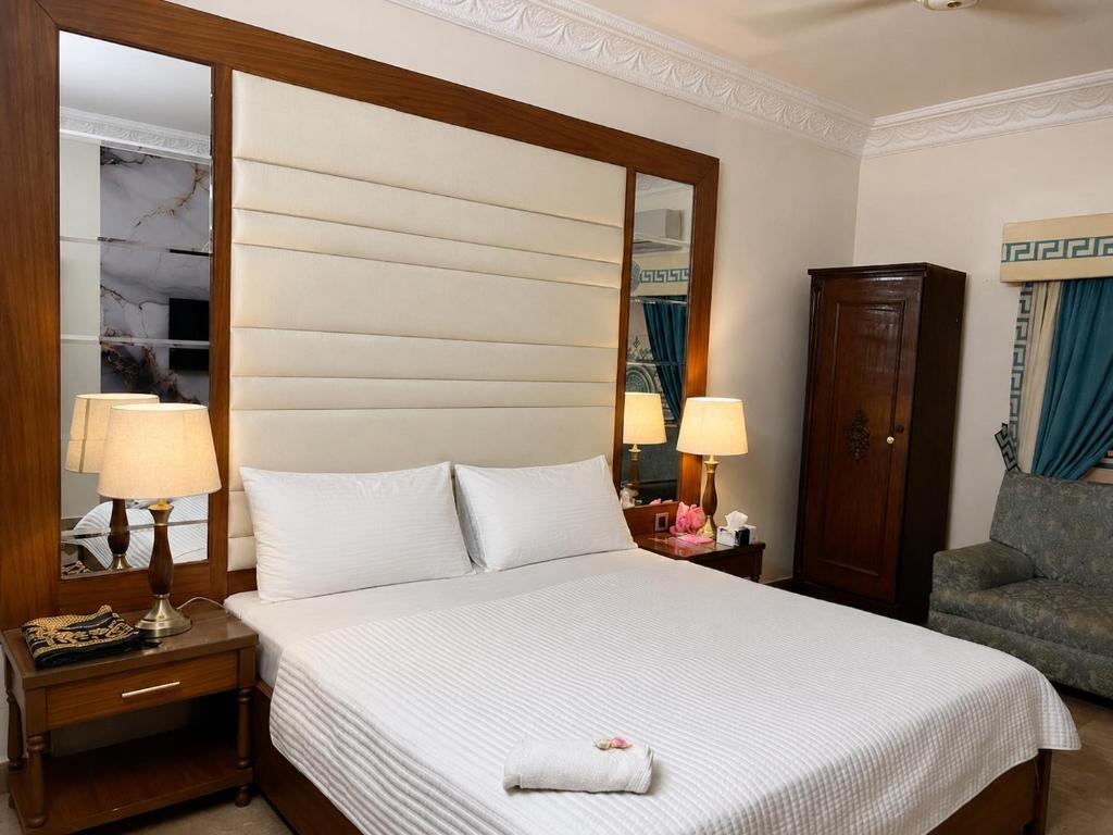 a bedroom with a large bed and a chair at Hotel Imperial Karachi in Karachi