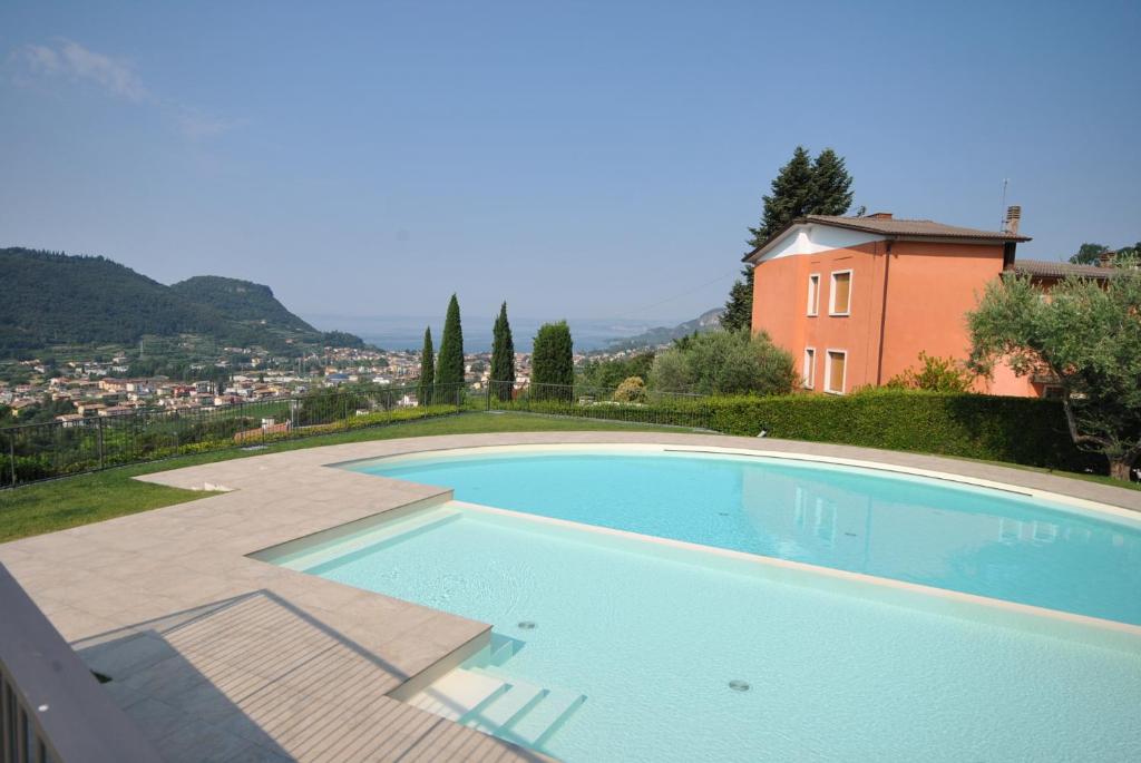 a swimming pool in front of a house at ApartmentsGarda - Baia D'Argento Residence in Costermano