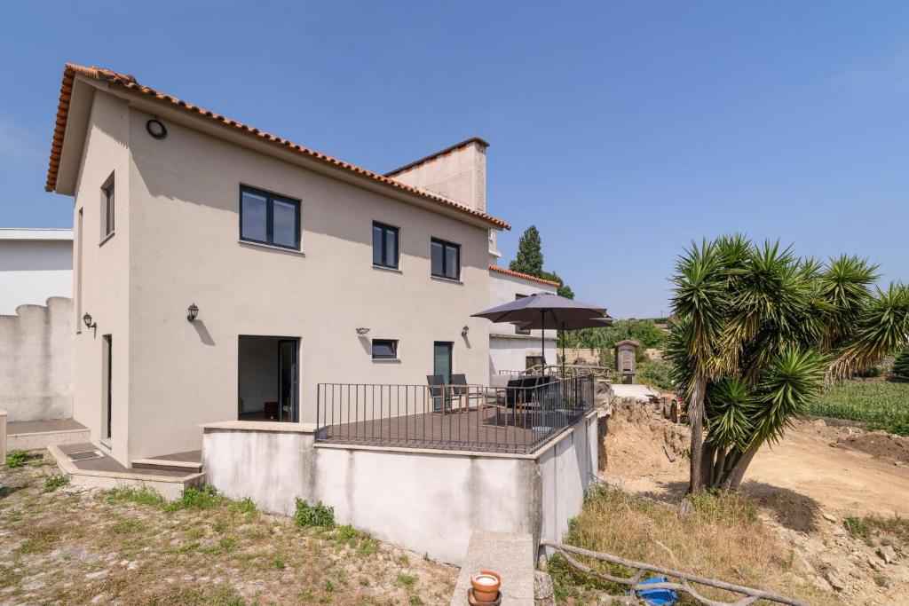 a white house with a table and a palm tree at Casa Pitoresca - Refugio Esposende in Braga