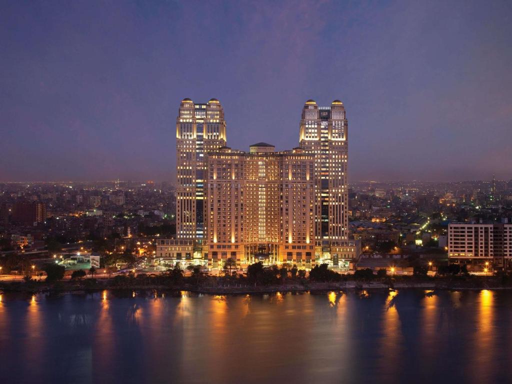a large building lit up at night next to the water at Fairmont Nile City in Cairo