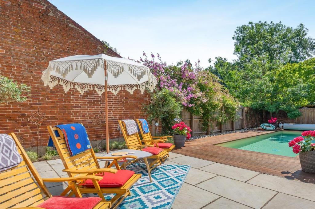 a group of chairs and an umbrella next to a pool at 2 Bed in Great Witchingham oc-p45227 in Reepham