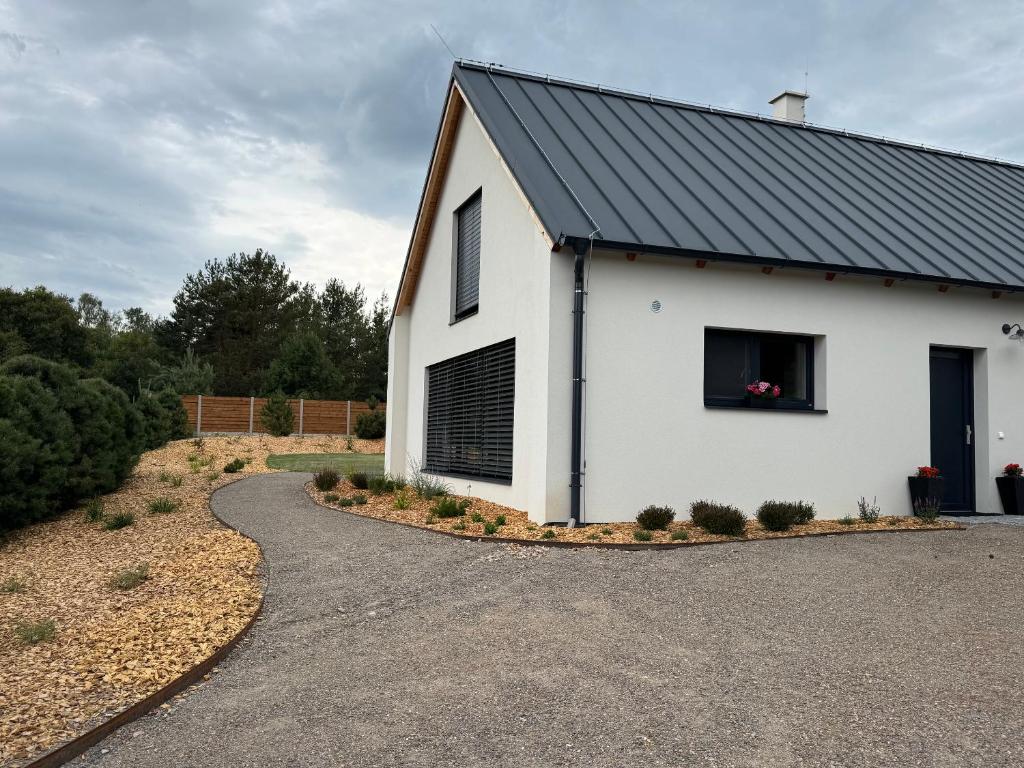 a white house with a black roof and a driveway at Chalupa u lesa Rasochy 83 in Uhlířská Lhota