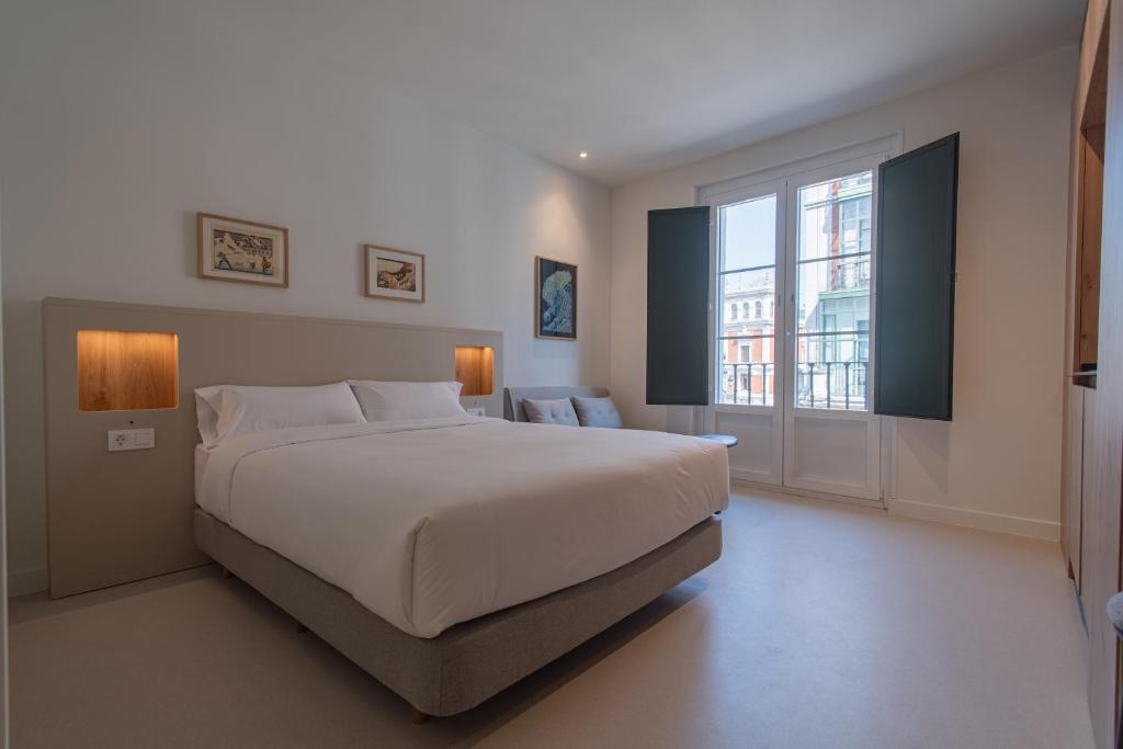 a bedroom with a large bed and a large window at Edificio Ferrari 4, by Plaza Mayor Apartamentos in Valladolid