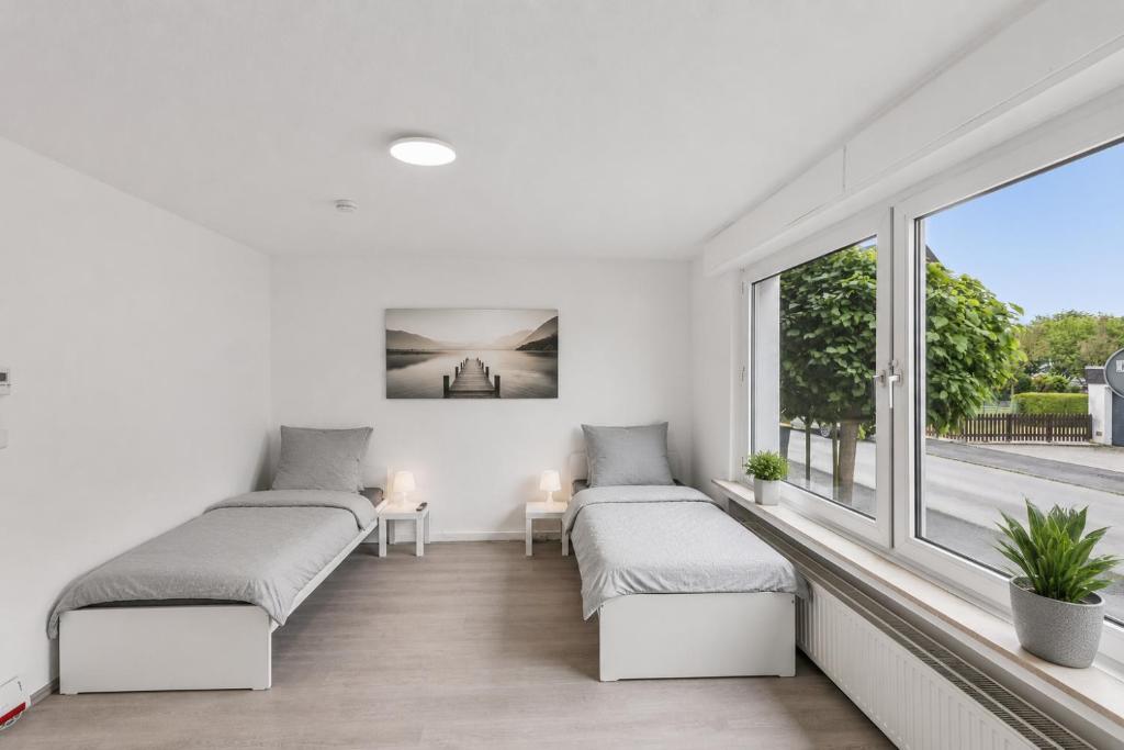 a white room with two beds and a window at NM living Lünen VII in Lünen