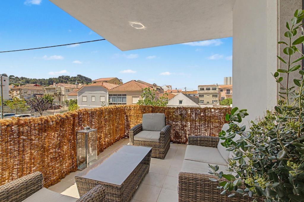a patio with wicker chairs and tables on a balcony at Trafaria Bliss in Trafaria