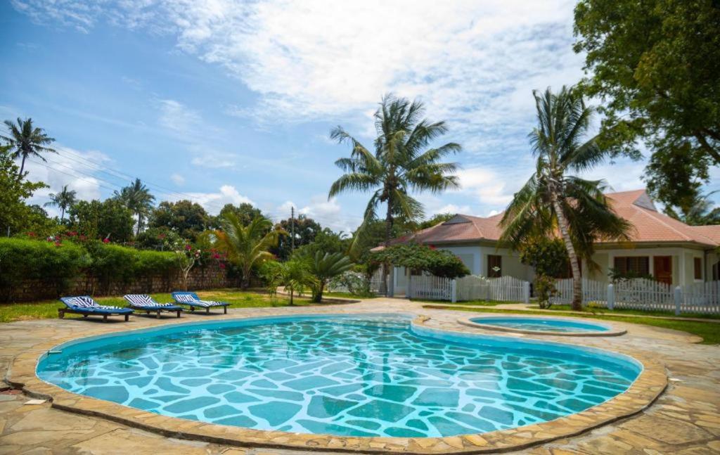 a swimming pool with two chairs and a house at Gabsgate Resort Kilifi in Kilifi