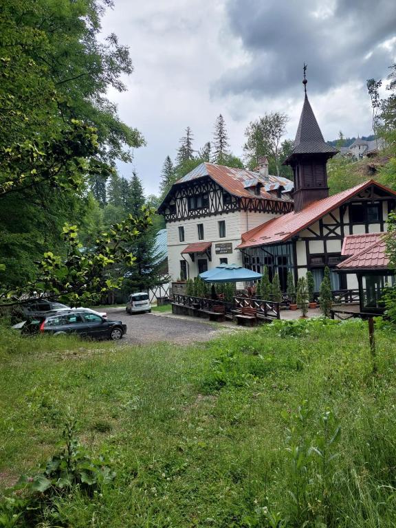ein großes weißes Gebäude mit einem Uhrturm neben einem Parkplatz in der Unterkunft Hotel Stavilar in Sinaia