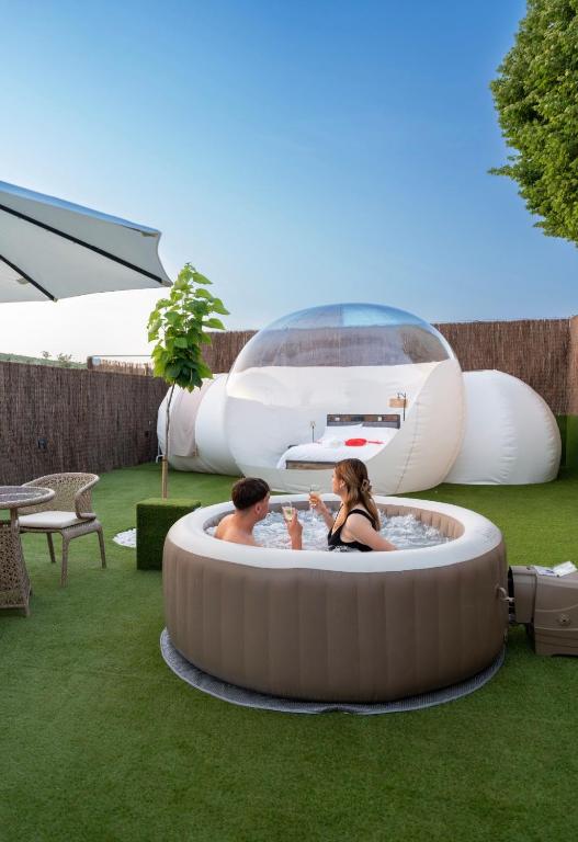 two people sitting in a hot tub in the grass at Burbuja El Sueño del Duque in Villanueva de Tapia