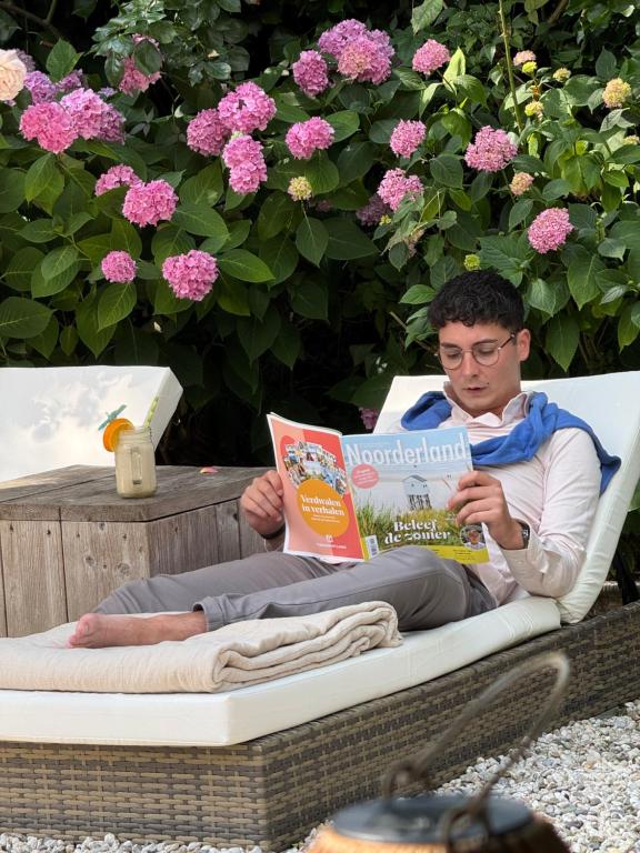 a man sitting in a chair reading a book at De Roos Leeuwarden Bloementuin & Biodynamisch Ontbijt in Leeuwarden